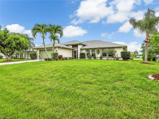 Spacious front yard with mature landscaping and a paved driveway leading to a two-car garage.