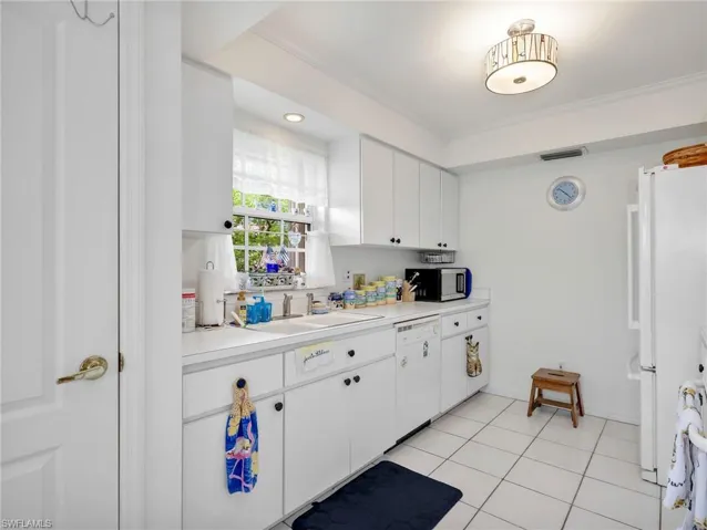 Kitchen featuring white cabinetry, white countertops, a double-basin sink, an integrated dishwasher, and tile flooring