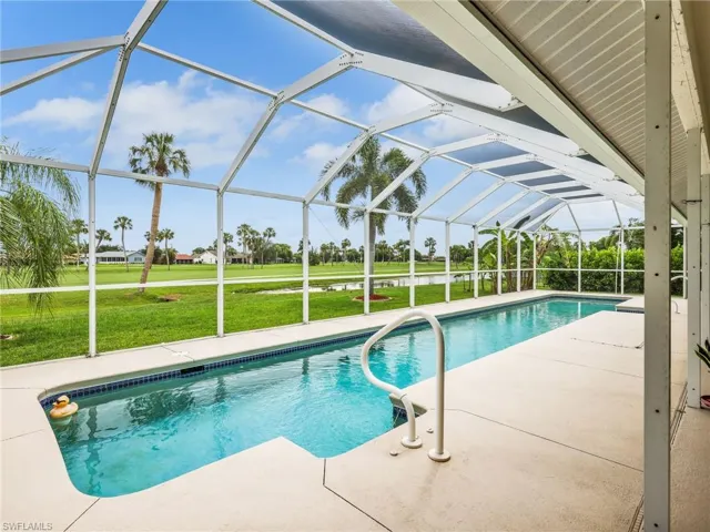 Screened-in lap swimming pool with a concrete deck and integrated grab rails
