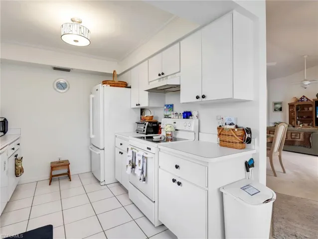 Kitchen featuring white cabinetry, white appliances, white countertops, and tile flooring