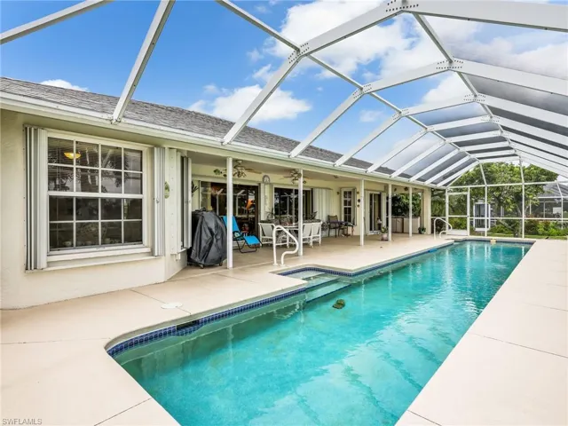 Screened swimming pool with integrated steps, surrounded by a spacious concrete patio