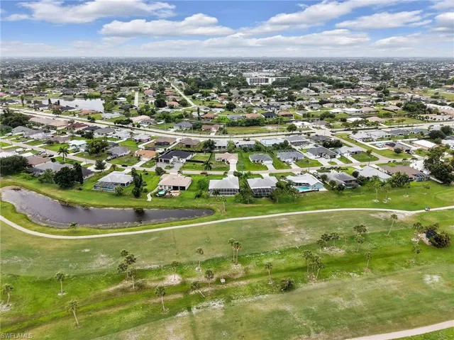 Expansive aerial perspective showcasing a residential neighborhood bordering a golf course