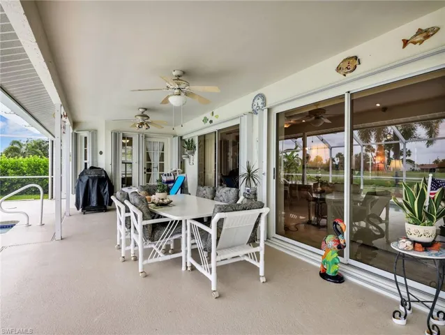 Expansive screened patio featuring a textured concrete surface, white ceiling fans, and multiple sets of sliding glass doors