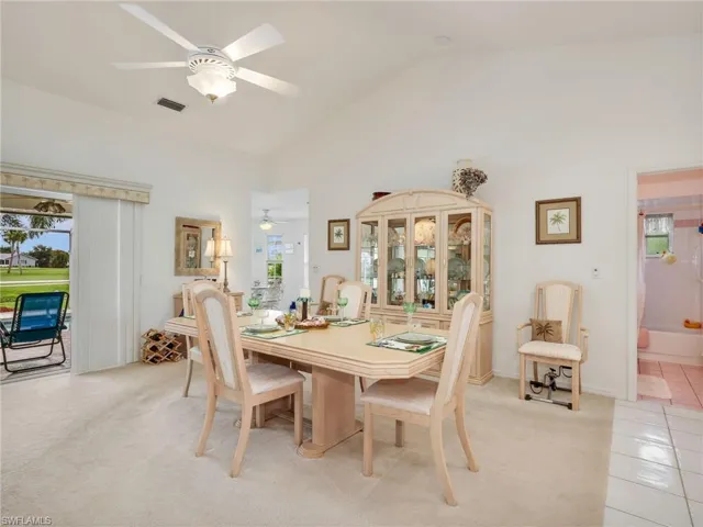 Vaulted ceiling dining area featuring light-toned carpeting and a ceiling fan with integrated lighting