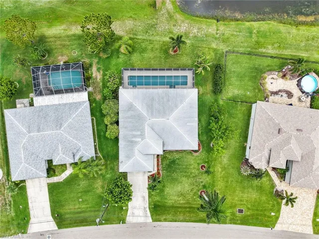 Aerial view, private backyard, showcasing a property with a grey shingle roof, a screened-in swimming pool, and a concrete driveway