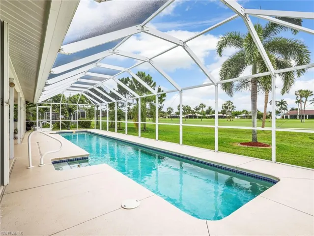 Screened-in swimming pool with a paved deck and integrated handrails