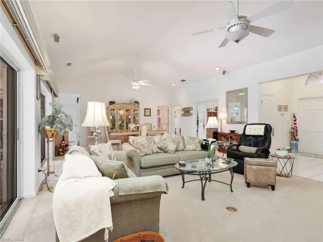 Spacious living area featuring vaulted ceilings with ceiling fans, recessed lighting, and light-colored carpeting