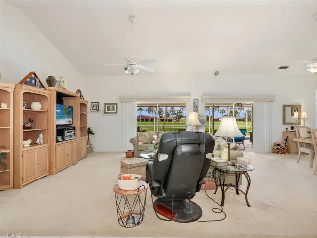 Spacious living area featuring a vaulted ceiling and light-toned carpeting