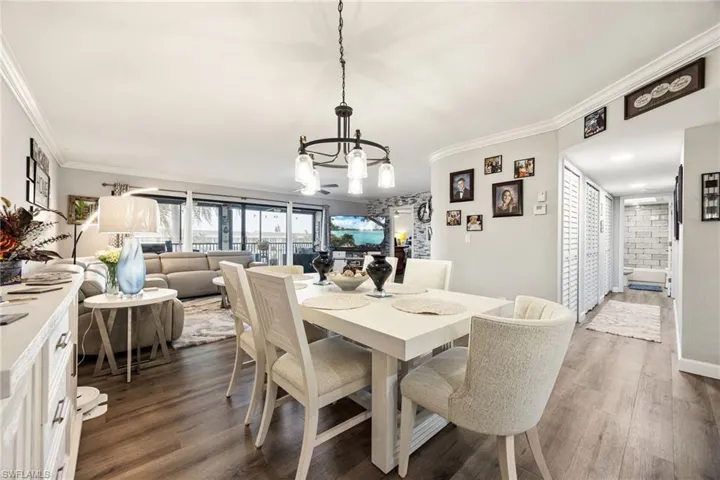 Open-concept living and dining area featuring wood-finish flooring, crown molding, a built-in buffet, and a sliding glass door leading to an outdoor space