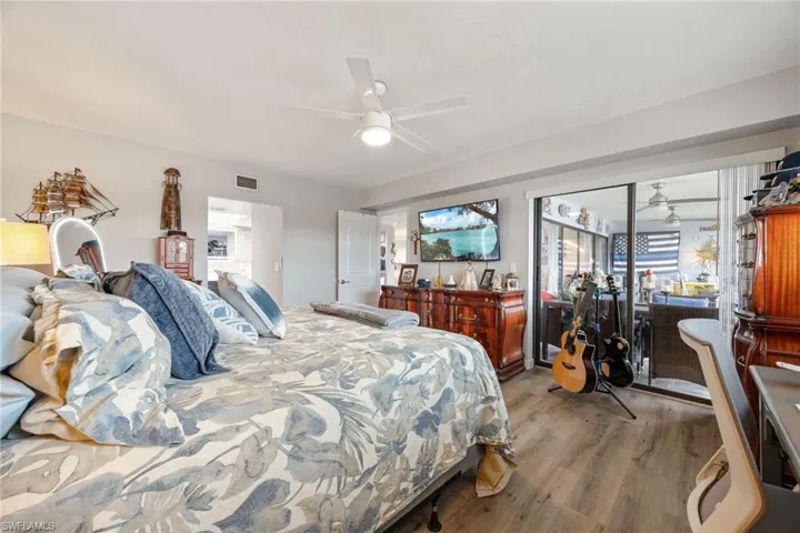 Bedroom featuring wood-finish flooring, a ceiling fan with integrated lighting, and direct access to an enclosed lanai through sliding glass doors
