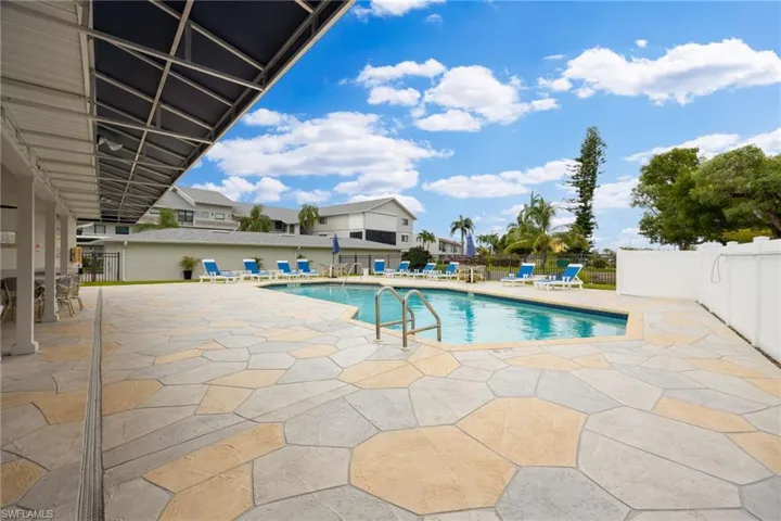 Swimming pool with stainless steel handrails, surrounded by a flagstone-patterned patio
