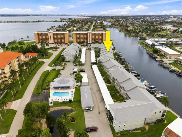 Waterfront condominium building with boat docks, covered parking, and an outdoor swimming pool