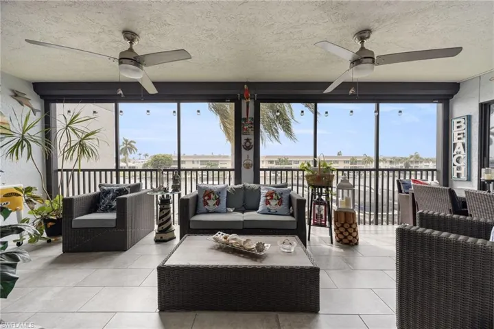 Screened lanai featuring tile flooring, two ceiling fans with integrated lighting, and panoramic exterior views