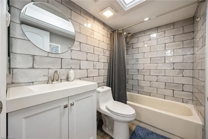 Bathroom featuring light-toned brick-patterned wall tiling