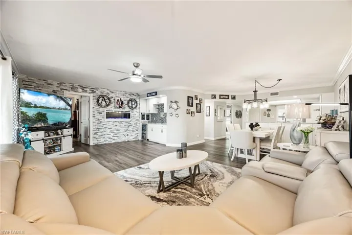 Open-concept living space featuring wood-finish flooring, a stone accent wall, and recessed lighting