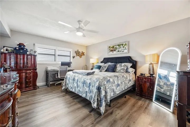 Bedroom featuring wood-finish flooring, a ceiling fan with integrated lighting, and window blinds