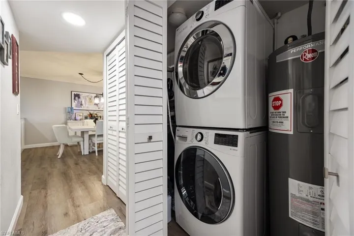 Dedicated laundry closet featuring a stacked washer and dryer, adjacent to a water heater, with louvered bi-fold doors