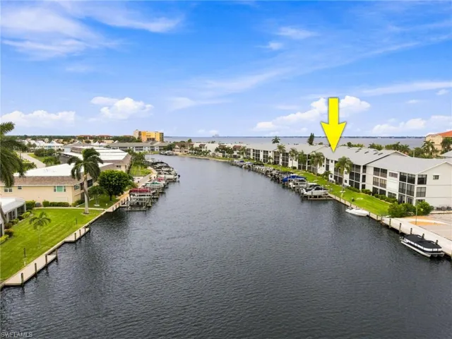 Waterfront condominium building featuring multiple private boat docks, covered parking, and direct canal access