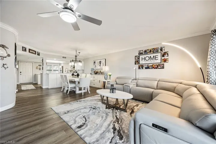 Open-concept living area featuring wood-finish flooring, crown molding, and a contemporary ceiling fan