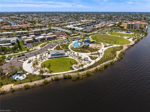 Waterfront community park featuring expansive green spaces, paved walking paths, and a dedicated splash pad area