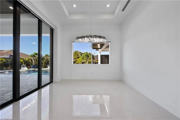 Empty room with a tray ceiling, recessed lighting, and light tile patterned floors