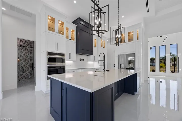 Kitchen featuring glass insert cabinets, pendant lighting, white cabinets, light stone countertops, and recessed lighting