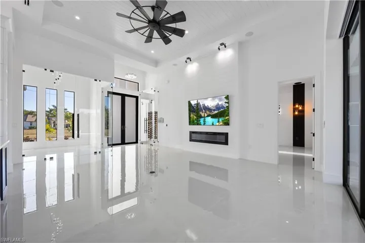Unfurnished living room with a high ceiling, wood ceiling, a tray ceiling, a fireplace, and ceiling fan
