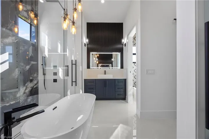 Bathroom with a marble finish shower, vanity, and a soaking tub