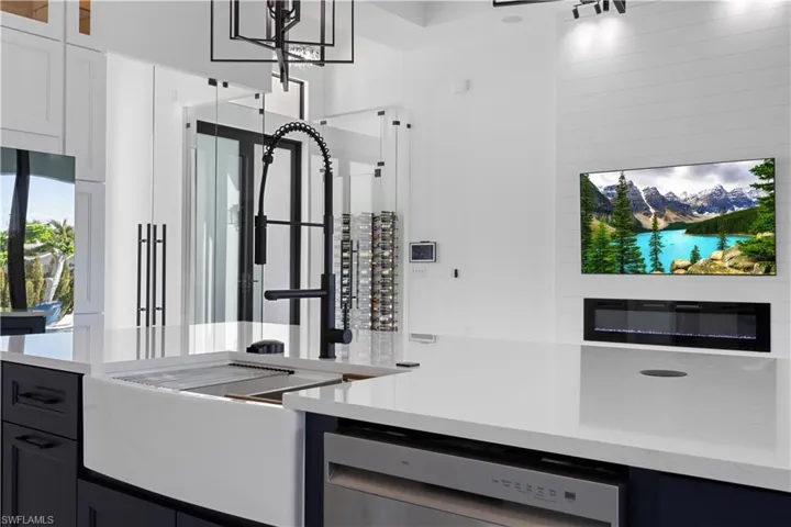 Kitchen with dishwasher, light stone countertops, and glass insert cabinets