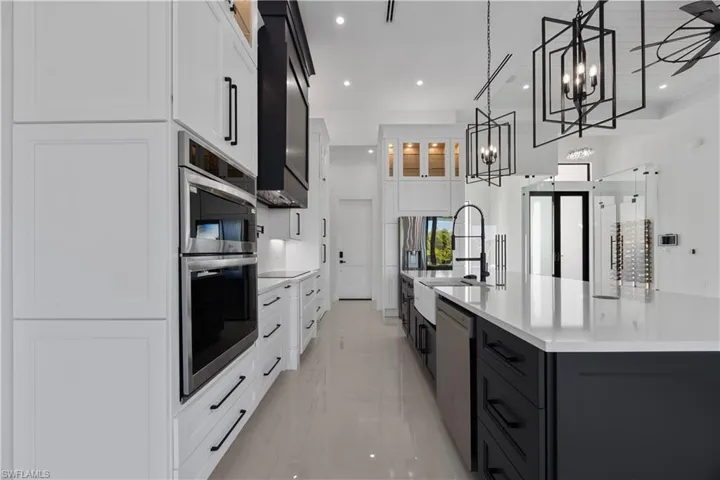 Kitchen featuring white cabinetry, glass insert cabinets, a large island, pendant lighting, and recessed lighting