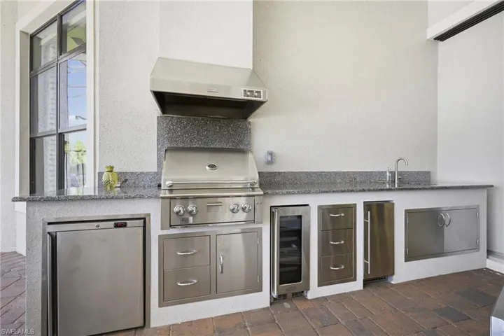 Summer kitchen with built-in grill, mini fridge, wine cooler, & ice machine.