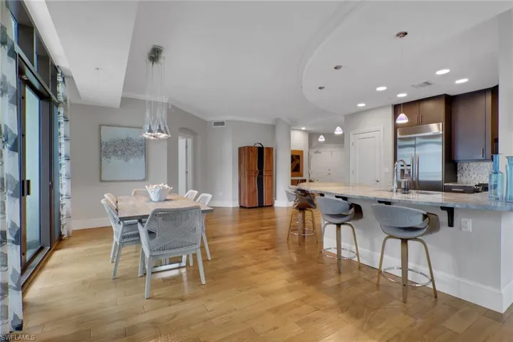 Kitchen with light stone counters, a breakfast bar, pendant lighting, a peninsula, and tasteful backsplash
