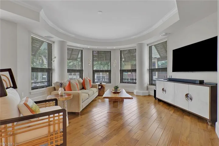 Living room featuring ornamental molding, light wood-style floors, and a raised ceiling