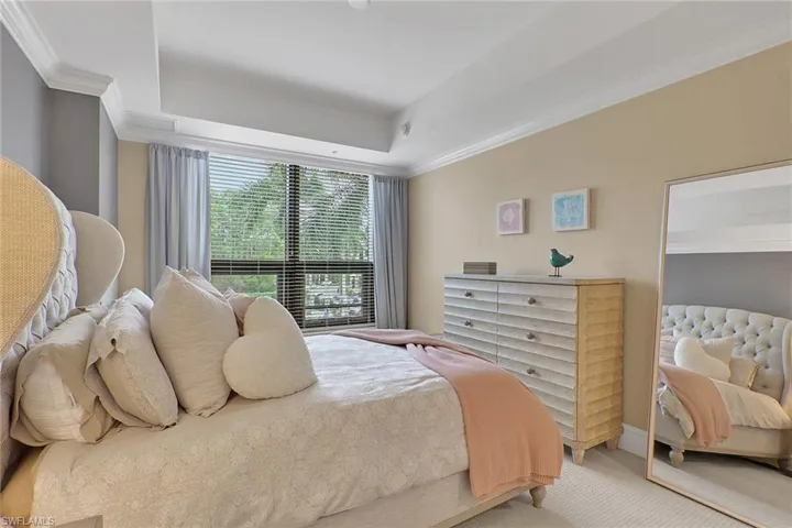Carpeted bedroom with crown molding and a tray ceiling