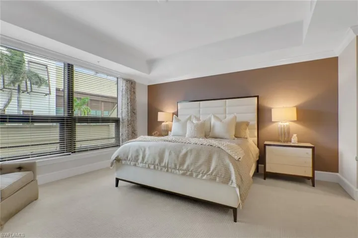 Carpeted bedroom with baseboards and a raised ceiling