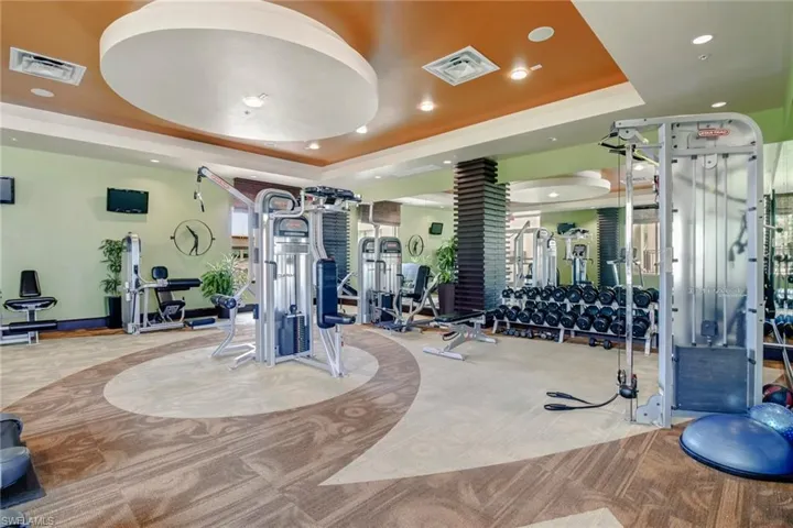 Workout area with a tray ceiling and recessed lighting