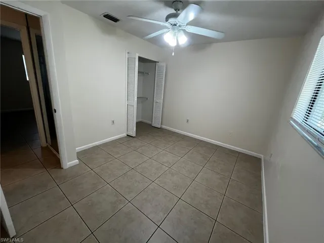 Guest bedroom with ample closet and lighted ceiling fan.