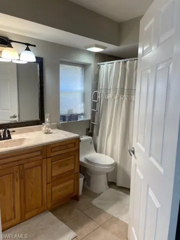 Full bathroom with a shower with shower curtain, vanity, and light tile patterned flooring