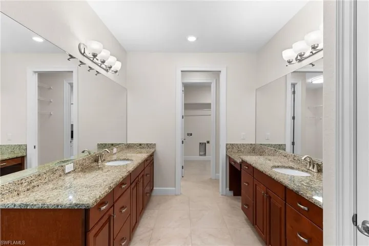 Bathroom featuring two vanities, a spacious closet, recessed lighting, and light tile patterned floors