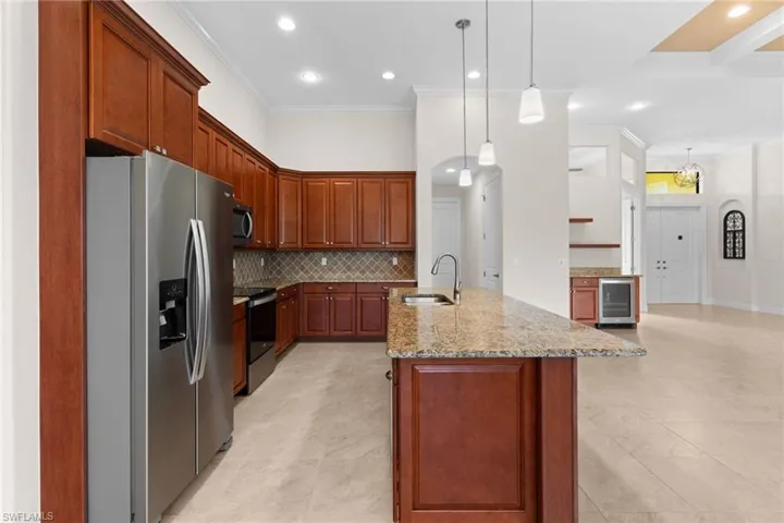 Kitchen with appliances with stainless steel finishes, light stone counters, crown molding, tasteful backsplash, and recessed lighting