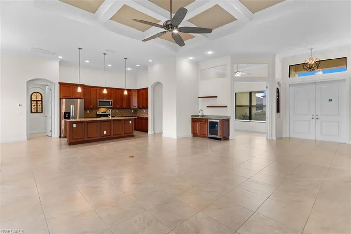 Open concept Great Room with arched walkways, coffered ceiling, crown molding, recessed lighting, and wet bar with wine cooler