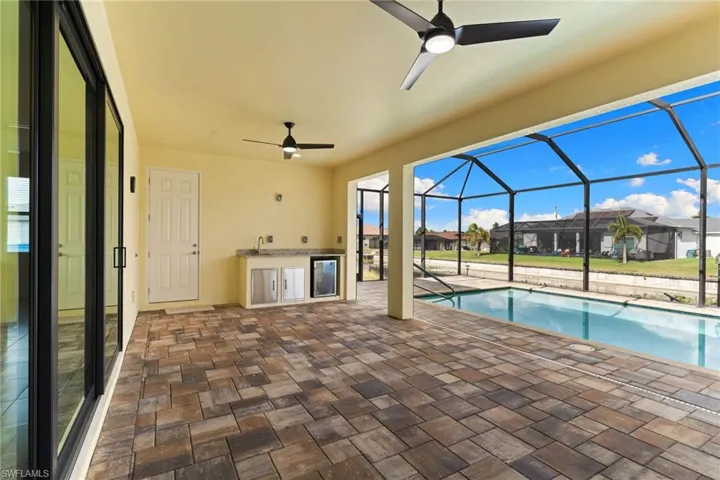 Outdoor pool with an outdoor kitchen, a patio, and screen enclosure