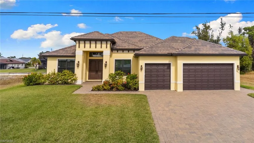 View of front of house featuring decorative driveway, a front lawn, a garage, and stucco finish