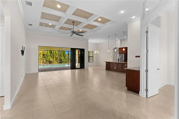 Living room featuring coffered ceiling, a high ceiling, a chandelier, a ceiling fan, and beam ceiling