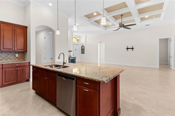 Kitchen featuring arched walkways, stainless steel dishwasher, decorative backsplash, decorative light fixtures, and crown molding