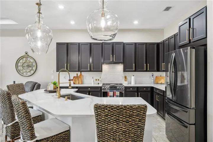 Kitchen with sink, decorative light fixtures, appliances with stainless steel finishes, and a kitchen breakfast bar