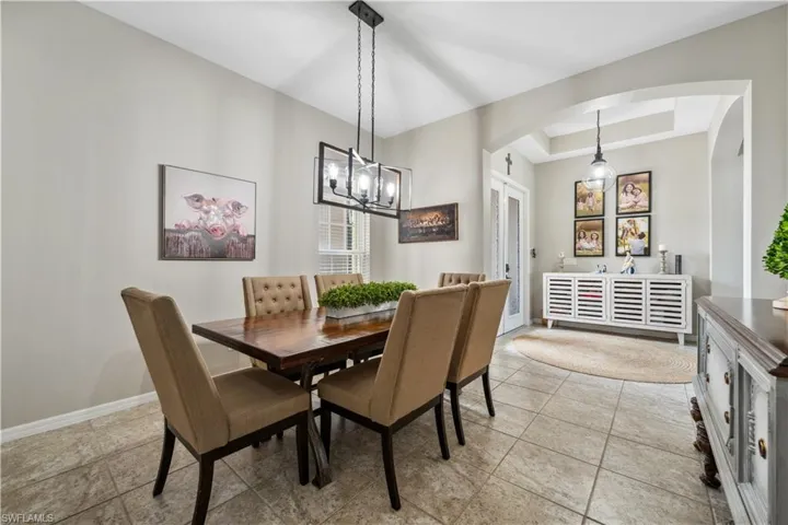 Dining area with a notable chandelier, light tile patterned floors, and a tray ceiling