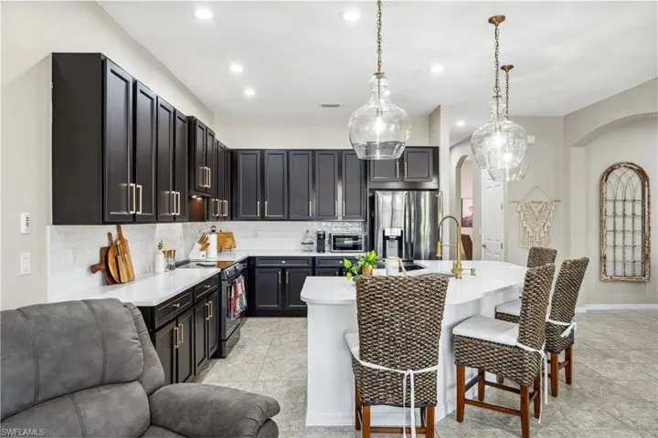 Kitchen featuring decorative light fixtures, stainless steel appliances, sink, decorative backsplash, and a breakfast bar