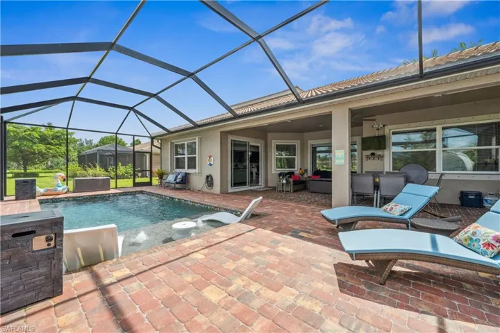 View of swimming pool featuring a lanai, a patio area, an outdoor kitchen, and ceiling fan