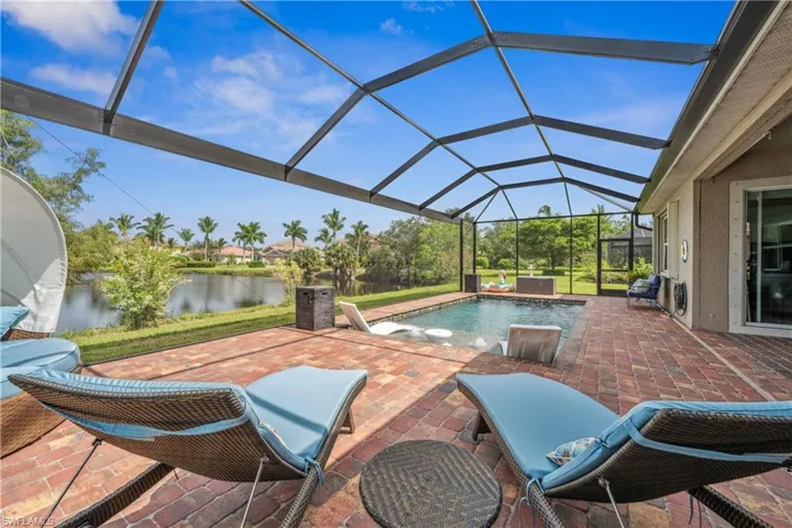 View of pool featuring a water view, a hot tub, a lanai, and a patio area